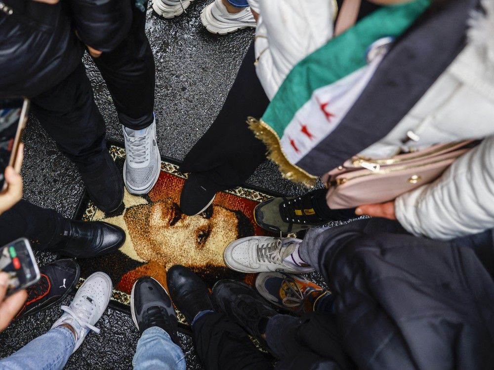 People stomp on a photo of Bashar Assad