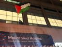 An anti-Israel protester waves a Palestinian flag from a window of Mount Sinai Hospital in Toronto, February 2024.