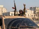 An anti-government fighter gestures from a vehicle patrolling the streets of Hama after rebel forces captured the central Syrian city, on Dec. 6, 2024.
