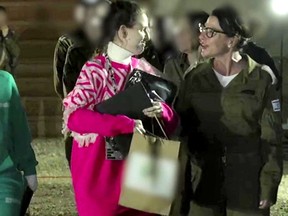 A women, at left, wearing pink talks to a women in a military garb