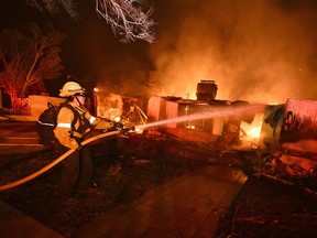 A firefighter sprays water on a burning home