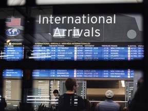 People look at flight information in an airport.