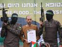 Hamas terrorists escort Israeli hostage Or Levy on a stage before handing him over to a Red Cross team in Deir el-Balah, central Gaza, on February 8, 2025.