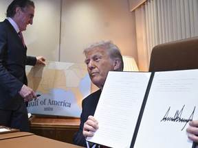 Donald Trump shows off a proclamation he signed as a staffer replaces a placard map behind him