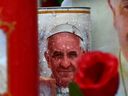 Candles depicting Pope Francis are placed at the statue of John Paul II outside the Gemelli hospital where Pope Francis is hospitalized in Rome on February 24, 2025.