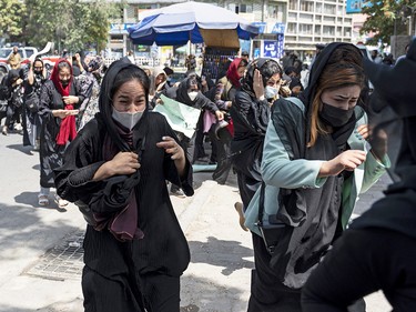 Afghan women protesting for their rights in Kabul on Aug. 13, 2022, run for cover as Taliban fighters fire into the air to disperse the crowd.