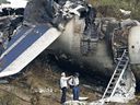 FILE: Investigators stand near the tail section of the Air France plane which crashed on landing, at Pearson airport in Toronto Wednesday Aug. 3, 2005.