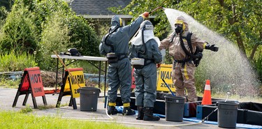Police officers in hazmat suits clean up while processing a fentanyl super lab outside Hamilton, Ontario, as part of Project Odeon.