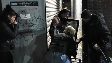 Staff at Toronto's Moss Park Consumption and Treatment Site carry a man inside their building, after he showed signs of overdosing on fentanyl, on Wednesday December 18, 2024.