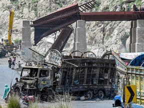A damaged vehicle blocks the road, below and destroyed overpass