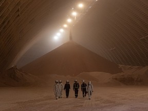 Workers walk away from a large pile of potash inside a storage facility