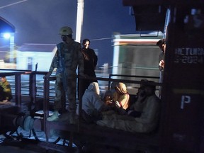 A Pakistani soldier and citizens on the back of a train at night