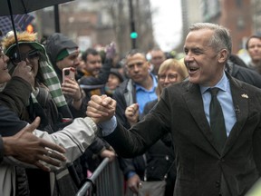 Canadian Prime Minister Mark Carney, right, shakes hands along a parade route