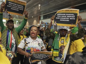 South Africans sing and a dance while holding signs in support of Ebrahim Rasool