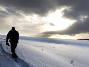RCMP office Jason Orr walks a path, that at points results in knee deep snow, to access the “slash”, a strip of cleared land that marks the Canada US border near Stanstead, Que.