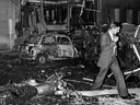 In this file photo taken on Oct. 3, 1980, an inspector walks amid car wreckage after a bomb exploded at the synagogue rue Copernic in Paris.