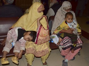 Two Pakistani women sit with children in their arms inside a railway station