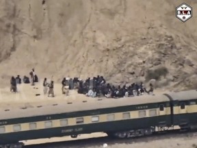 A screengrab showing people standing outside a train in a sandy region as seen from afar