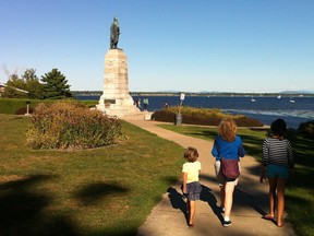 People walk towards a statue of overlooking a lake