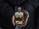 A Catholic nun shows the back cover of her mobile phone with a photograph of Pope Francis as she attends a nightly rosary prayer service for Pope Francis in St. Peter's Square at the Vatican, Thursday, March 6, 2025.