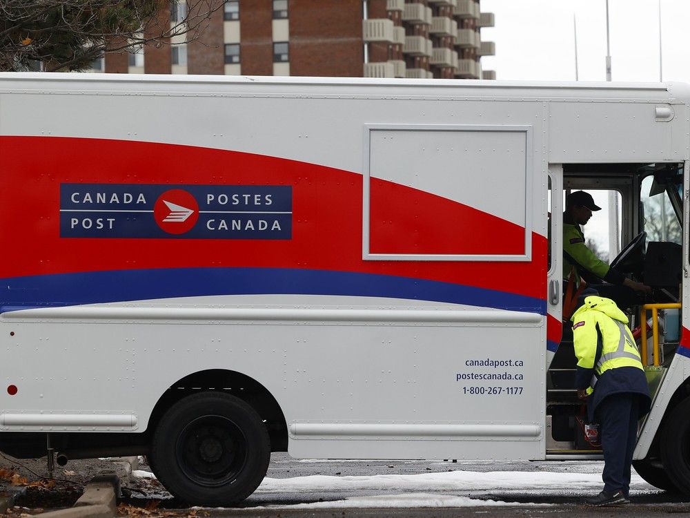 Canada Post employees work on getting a truck started to start work in Ottawa. Canada Post employees work on getting a truck started to start work in Ottawa.
