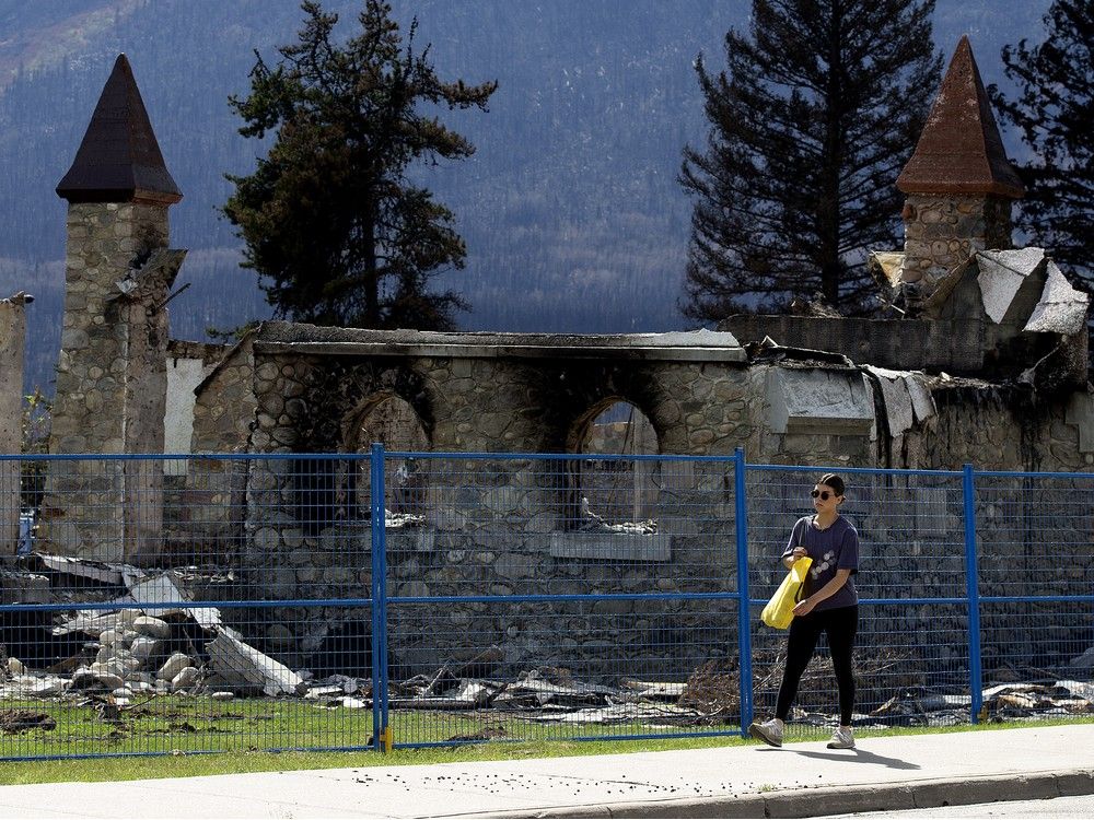  A pedestrian makes their way past what remains of Jasper’s St. Mary & St. George Anglican Church on Monday, Aug. 19, 2024.