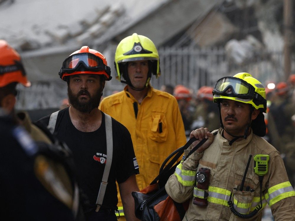 Israeli firefighters, not those shown, rescued a Canadian embassy worker from a building hit during the Iranian missile barrage on Tel Aviv over the weekend.
