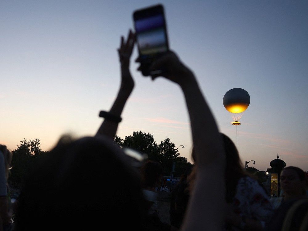  People watch as the Paris 2024 Olympic cauldron tethered to a balloon flies above the Tuileries garden at sunset during France’s annual street music festival, the Fete de la Musique, in Paris on June 21, 2025.