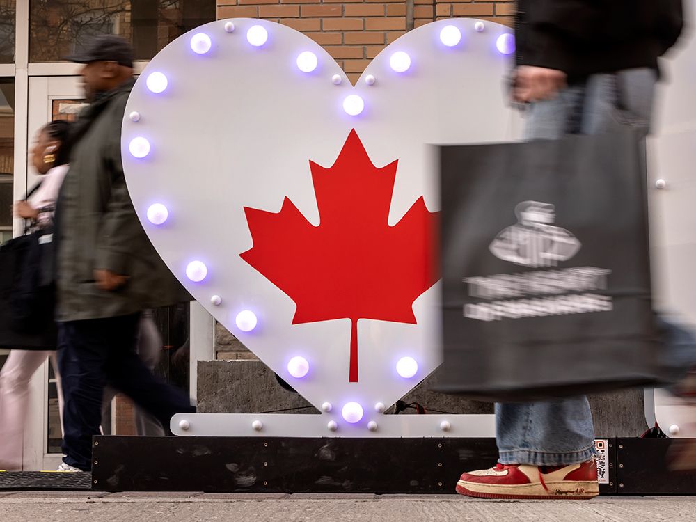  People walk past a Canadian maple leaf inside in a heart on Toronto’s Queen Street West amid the tariff war with the United States.