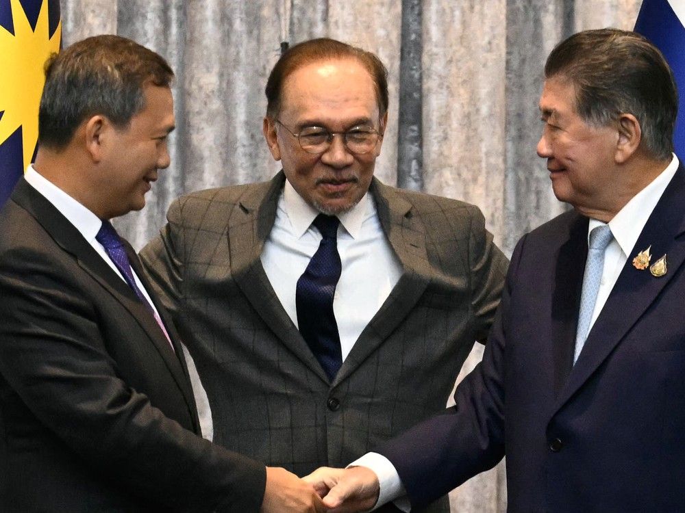  Cambodia’s Prime Minister Hun Manet, left, and Thailand’s acting Prime Minister Phumtham Wechayachai, right, shake hands as Malaysia’s Prime Minister Anwar Ibrahim puts his arms around them following a press conference after talks on a possible ceasefire between Thailand and Cambodia in Putrajaya on July 28, 2025.