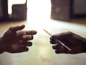 Two hands share a syringe