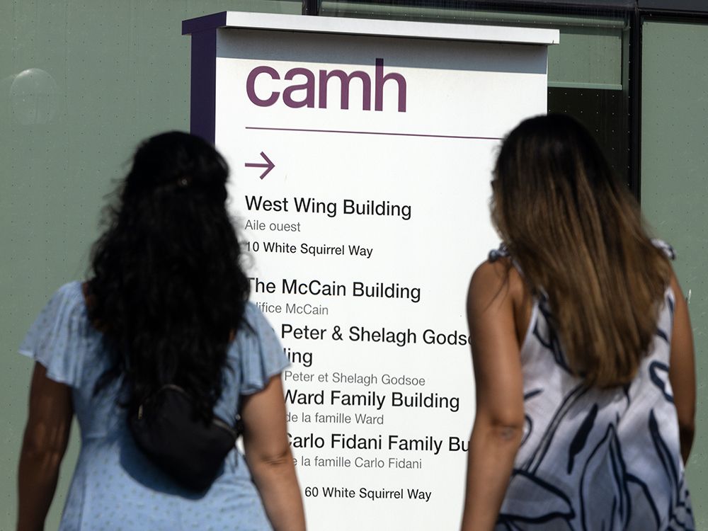 Two women read the a sign at the CAMH location on Queen Street ibn Toronto.