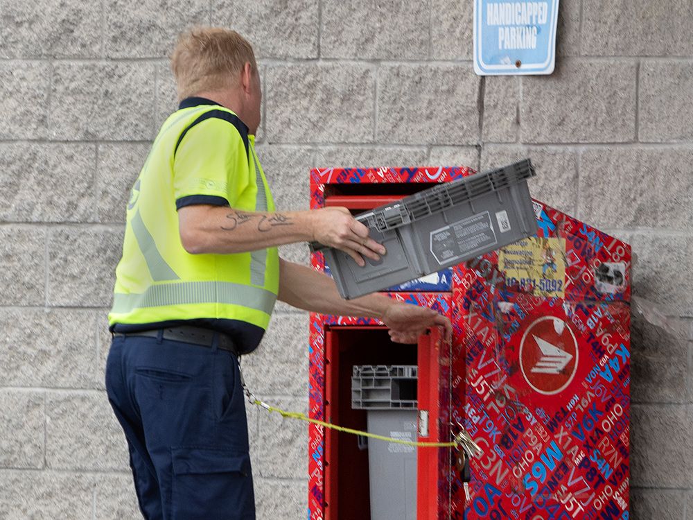 A Canada Post worker empties a mailbox in Toronto.
