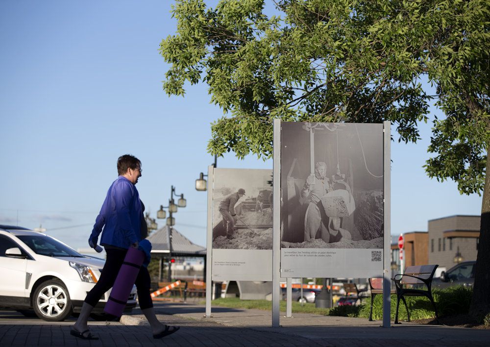  A pedestrian passes historic photographs in Arvida, Quebec.