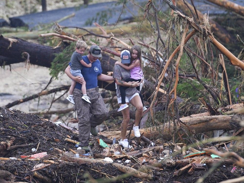  People climb over debris on a bridge atop the Guadalupe River after a flash flood swept through the area Saturday, July 5, 2025, in Ingram, Texas.