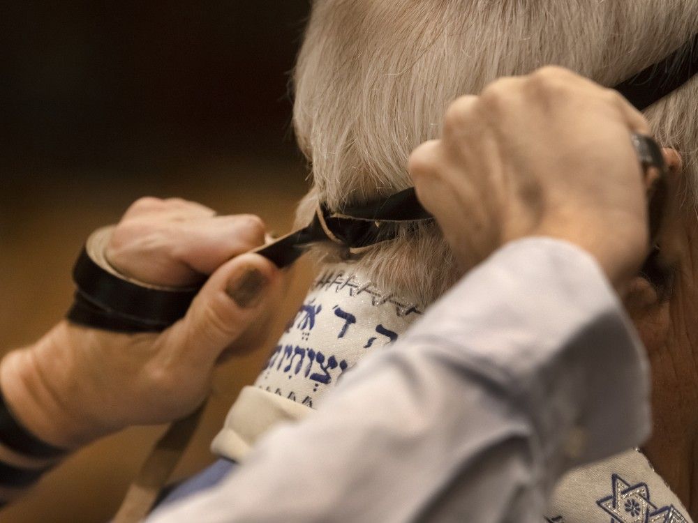  Tefillin is wrapped on a mans head as a reminder of the covenant with God in the Jewish faith prior to Addison Davidson’s bat mitzvah at Toronto’s Adath Israel Synagogue, Thursday December 14, 2023.