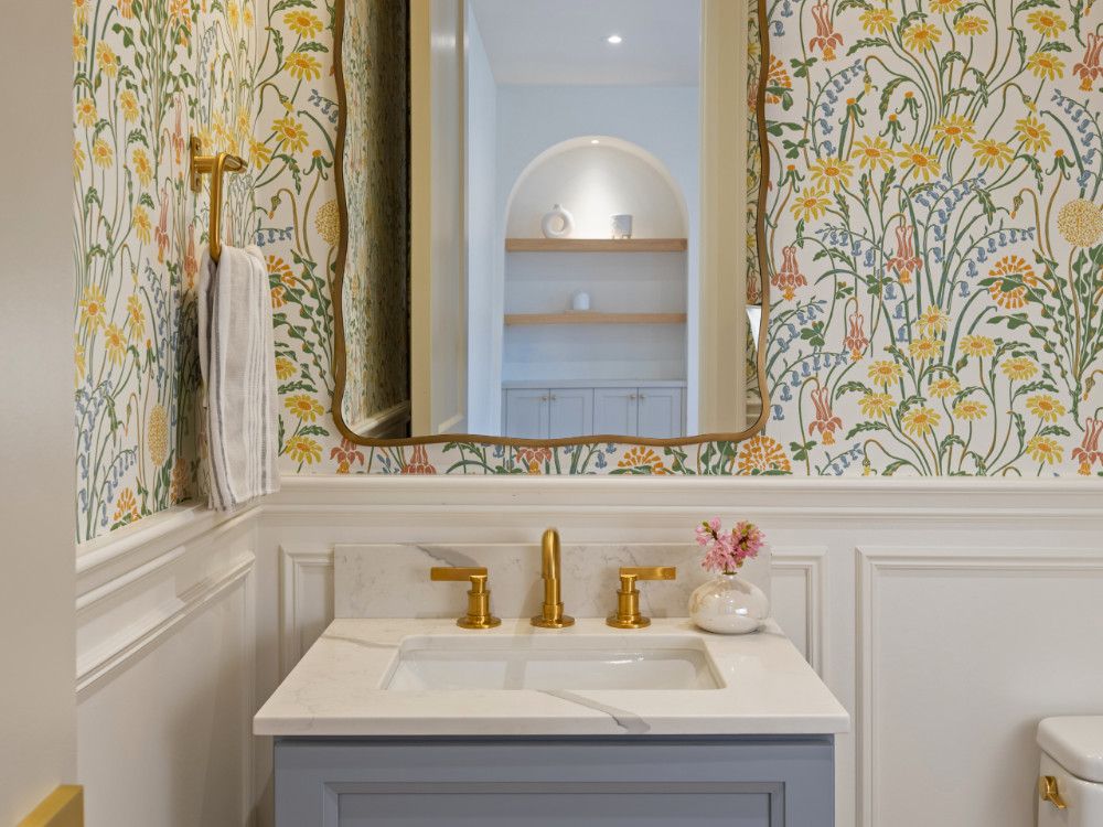 Wildflower Wallpaper sets the tone for a cheerful women's toilet, grounded by a periwinkle blue vanity and polished copper accents. Wildflower Wallpaper sets the tone for a cheerful women's toilet, grounded by a periwinkle blue vanity and polished copper accents.