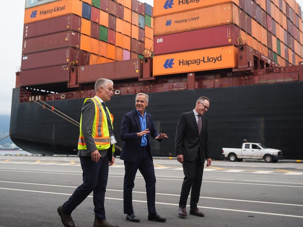Prime Minister Mark Carney is given a tour of a container terminal by Centerm chief operating officer Joel Werner, left, and Vancouver Fraser Port Authority President and CEO Peter Xotta, right, in Vancouver, Aug. 3.