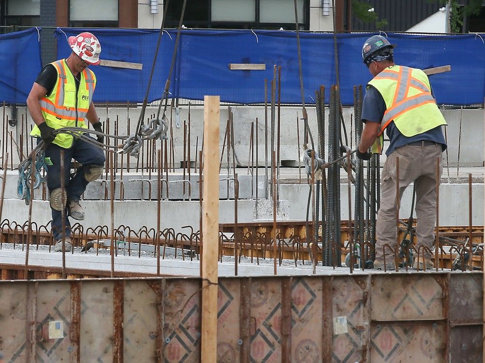 Workers are shown at the construction site of a condominium complex.