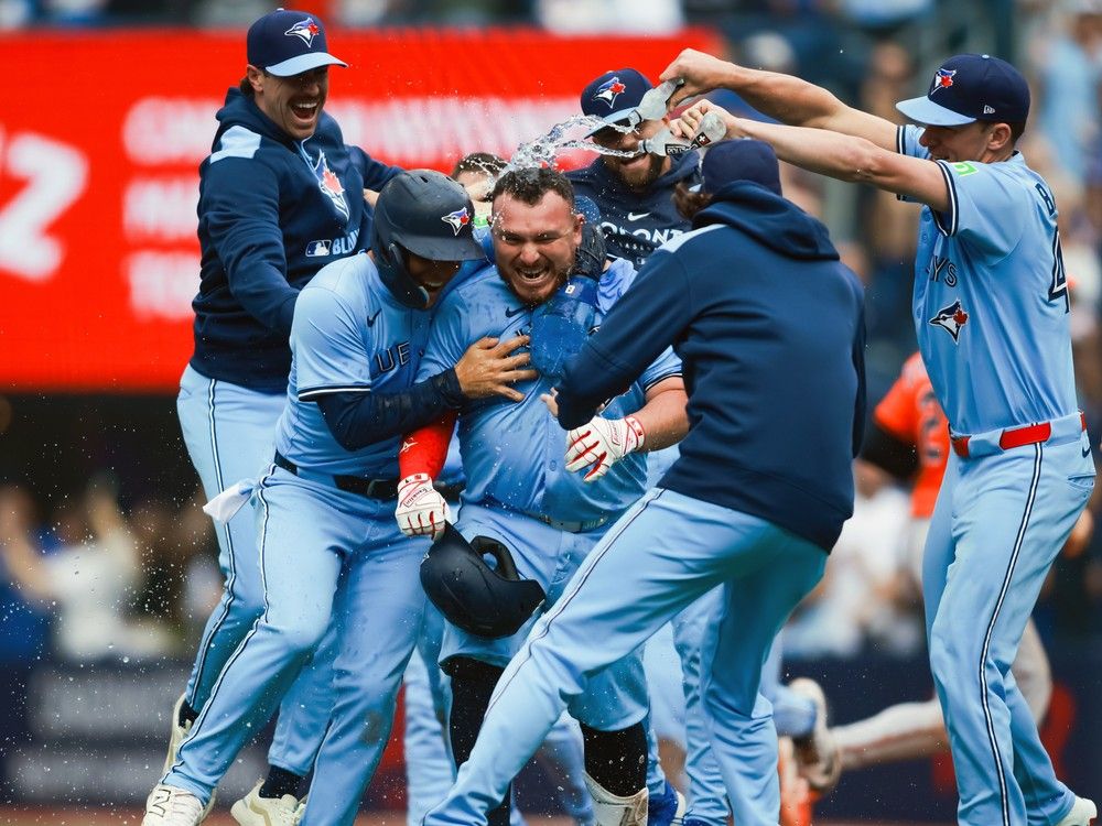  Toronto Blue Jays teammates mob Alejandro Kirk as they celebrate his walk-off sac-fly in a game against the Baltimore Orioles at Rogers Centre on Saturday. Toronto came from behind to win 5-4.