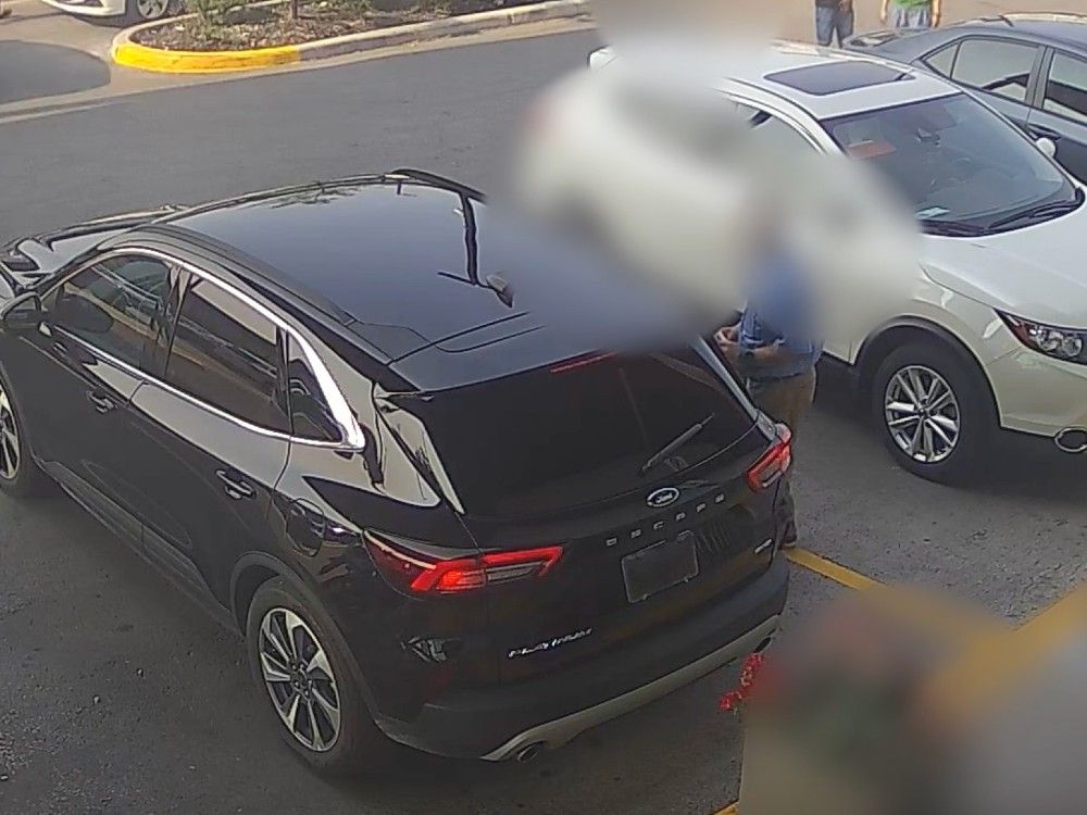  A victim of distraction theft stands in a parking lot when he is approached by a vehicle in this still image taken from a video shared by Toronto police.