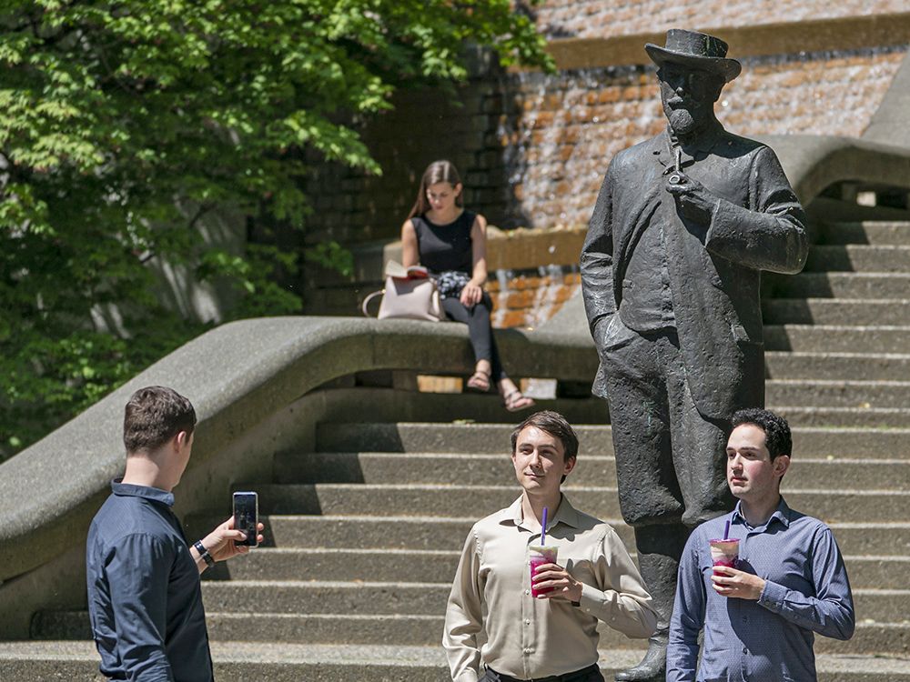  People pose for a photo with the statue of Judge Matthew Begbie outside BC Supreme Court in New Westminster in 2019. The statue has since been removed.