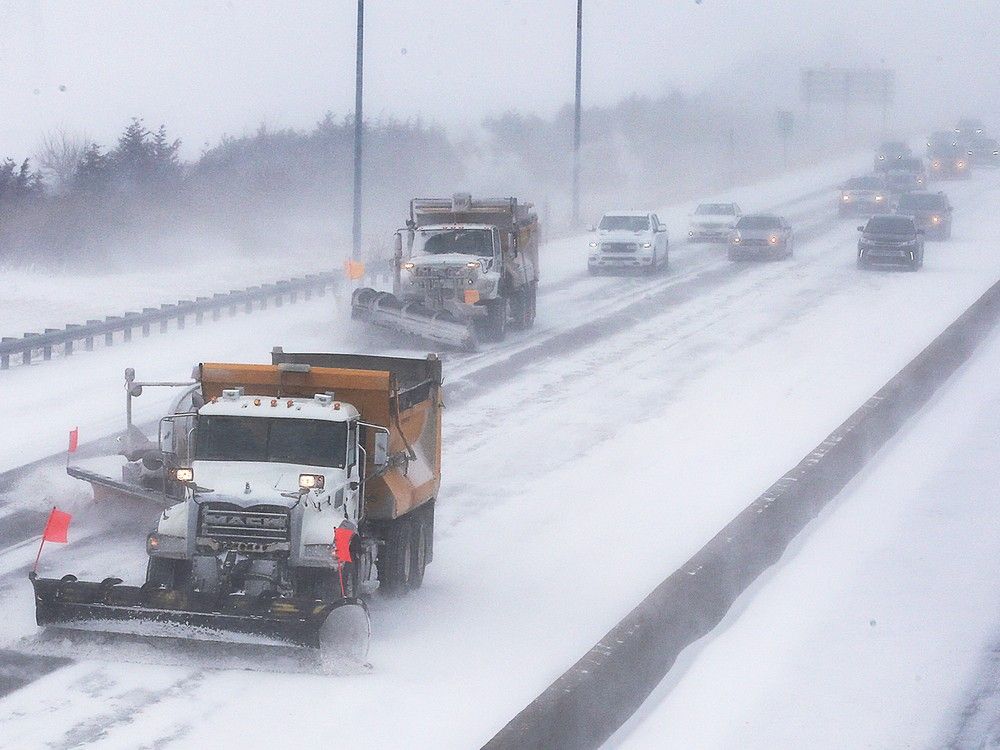  Traffic follows plows on a snow-covered Highway 401.