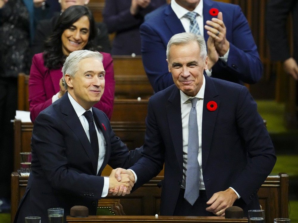 Finance Minister Francois-Philippe Champagne shakes hands with Prime Minister Mark Carney after delivering his budget speech in the House of Commons, in Ottawa, Tuesday, Nov. 4, 2025.