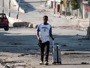 A Haitian msn pulls a suitcase.
