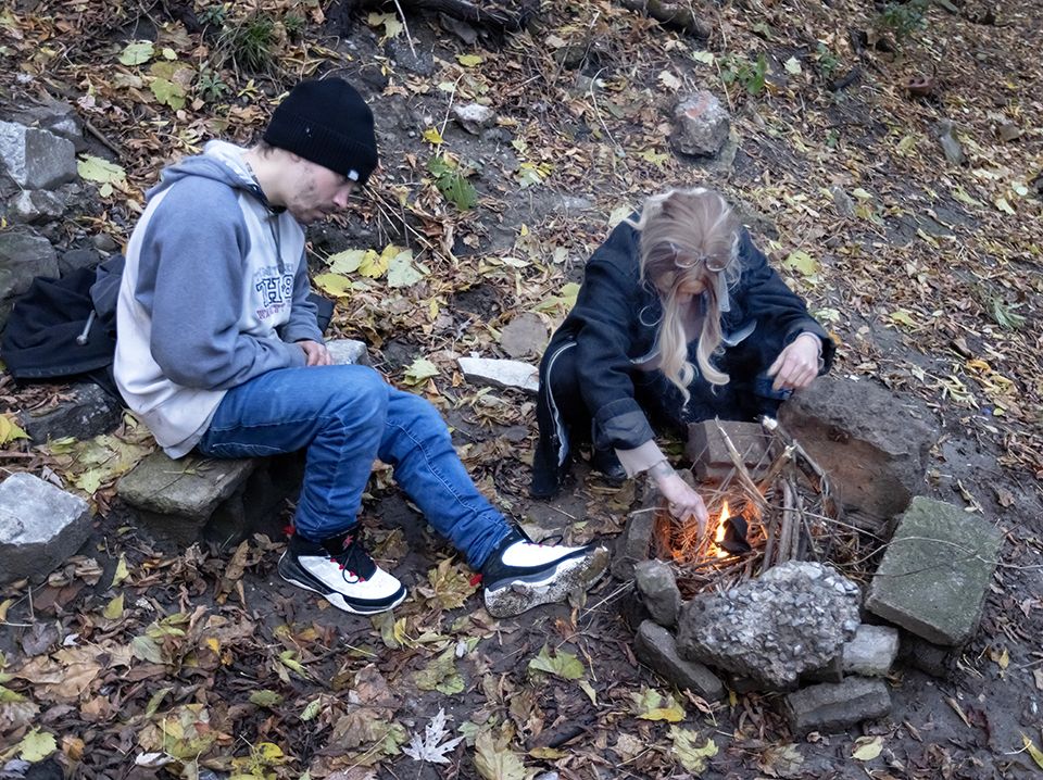 A homeless addict in St. Catharines, Ont., makes a fire while her friend, Nick, watches.