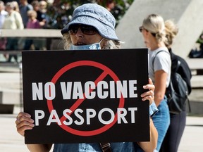 Woman holding 'No Vaccine Passport' sign.