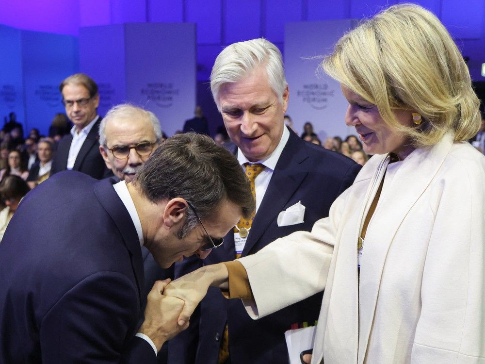  France’s President Emmanuel Macron kisses the hand of Queen Mathilde of Belgium as King Philippe of Belgium looks on during the World Economic Forum (WEF) annual meeting in Davos, Switzerland, on Tuesday.