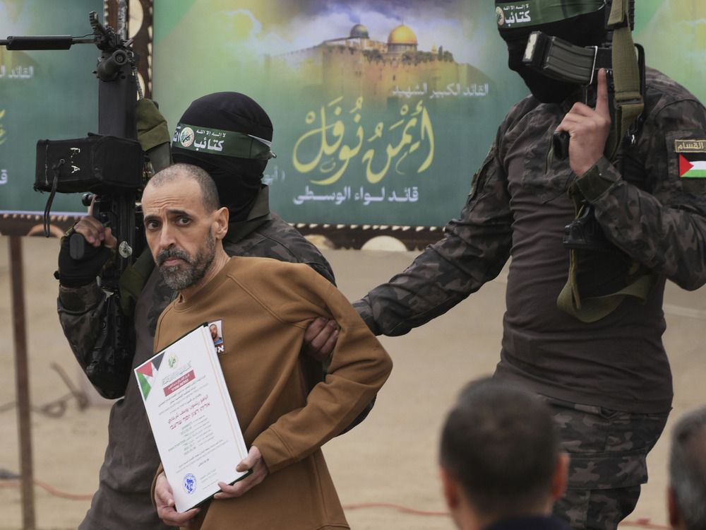  Eli Sharabi, who had been held hostage by Hamas in Gaza since October 7, 2023, is escorted by Hamas fighters before being handed over to the Red Cross in Deir al-Balah, central Gaza Strip, Saturday Feb. 8, 2025.