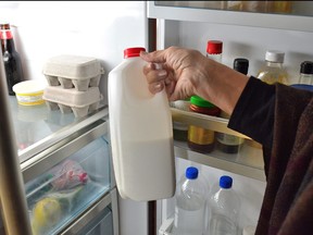 A person takes a jug of milk from the refrigerator